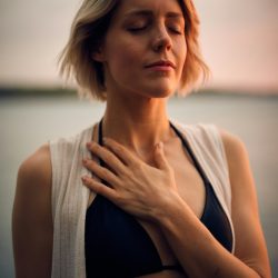 A lady with short hair putting her hand on her heart