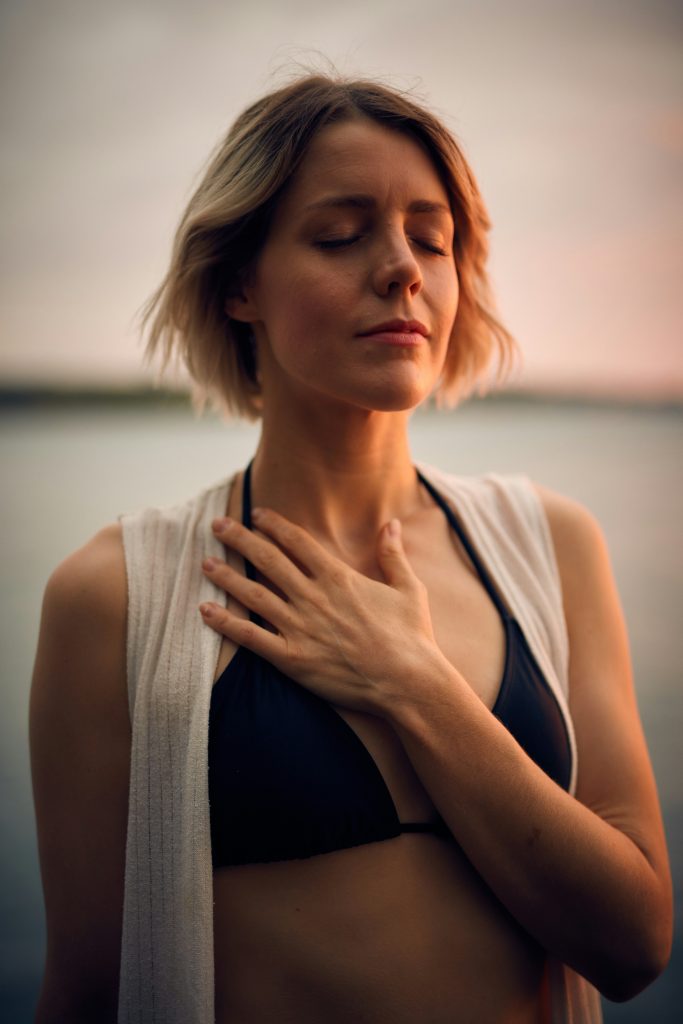 A lady with short hair putting her hand on her heart